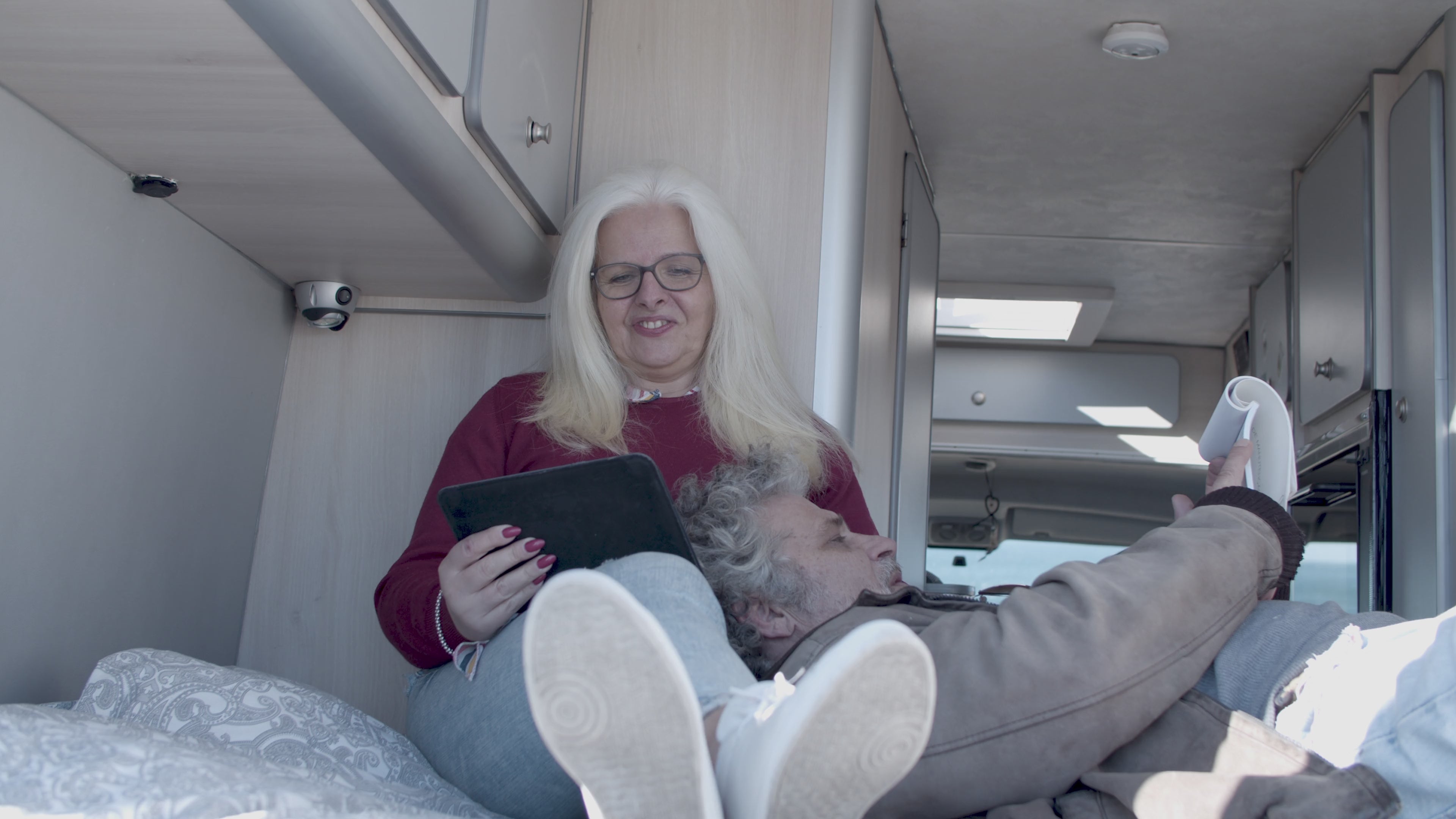 Older couple laying down in their RV  reading